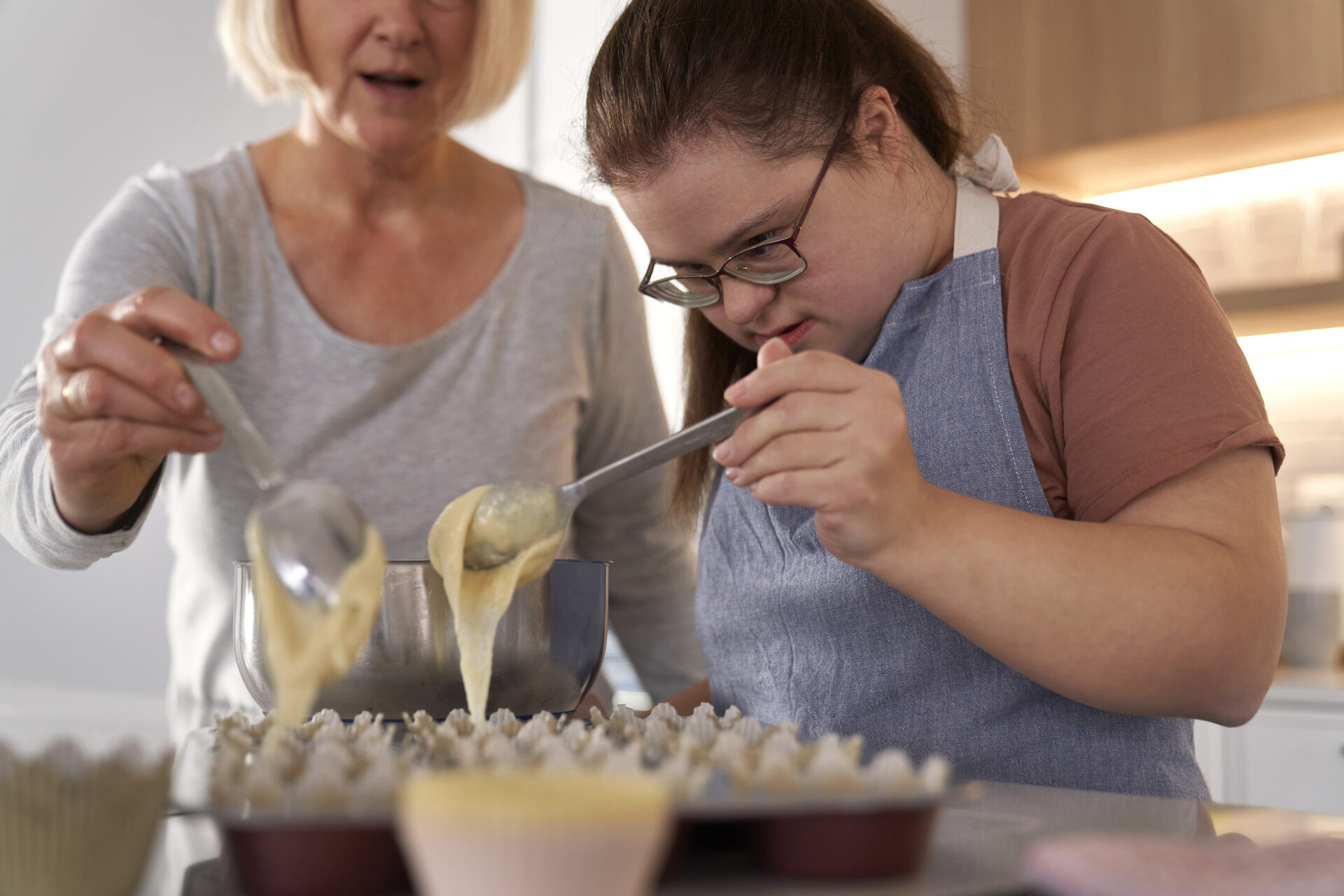 Down syndrome woman and her mother making homemade cupcakes