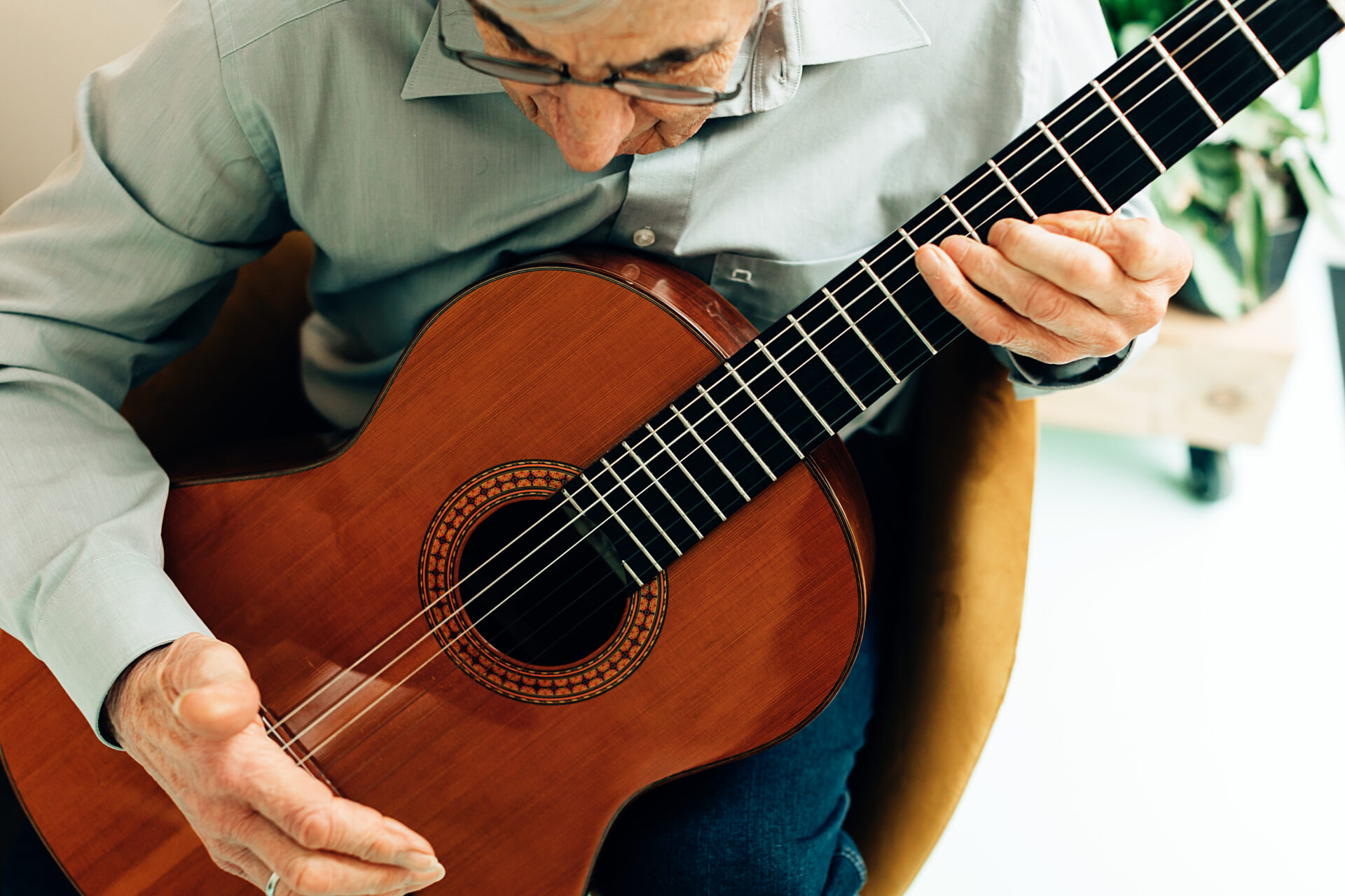 elderly man playing on acoustic guitar at home. senior person with music hobby.