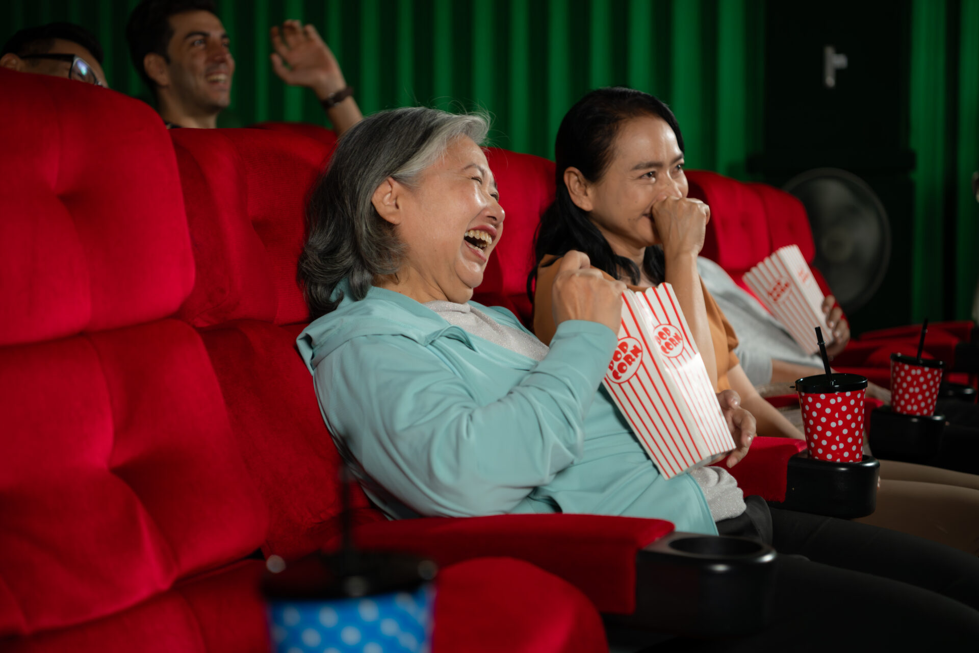 Group of asian senior friends watching comedy movie and laugh at the cinema with popcorn