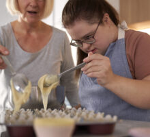 Down syndrome woman and her mother making homemade cupcakes