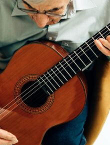 elderly man playing on acoustic guitar at home. senior person with music hobby.
