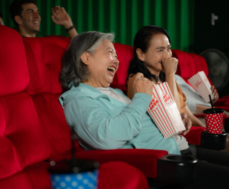 Group of asian senior friends watching comedy movie and laugh at the cinema with popcorn